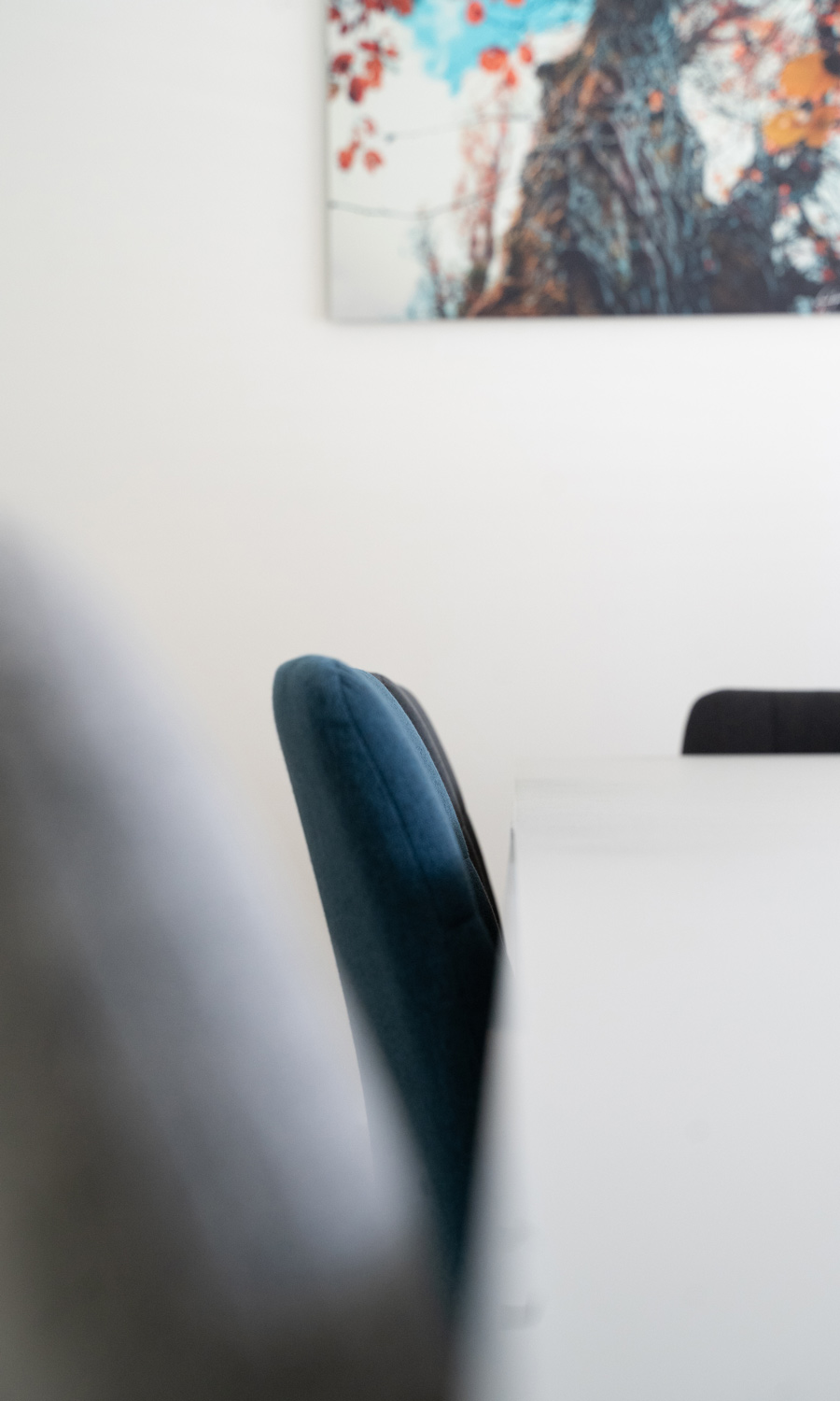 Focus sur une chaise de la salle de réunion de l'agence avec un tableau décoratif en fond